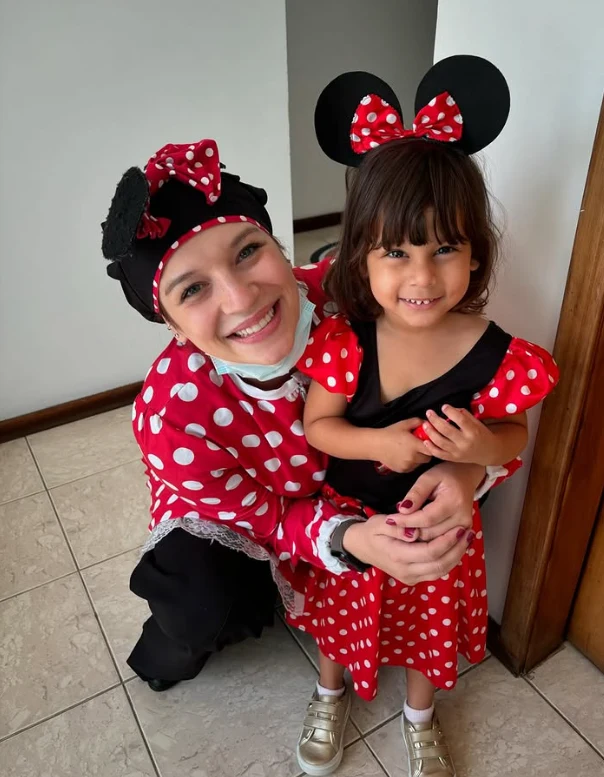 Dra. Rafaela Ayello fantasiada ao lado de uma criança sorrindo no consultório